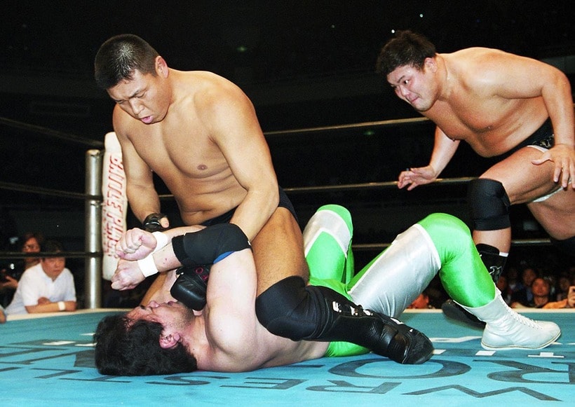 三沢光晴(下)にマウントパンチを見舞う小川直也に、後方からぶちかましを狙う力皇猛（2001年4月、日本武道館）