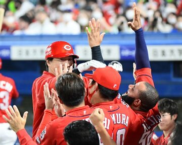  先制ソロを放ち、ベンチで祝福される広島・長野（奥）