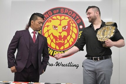 鷹木信悟（左）に腕に入った王冠マークを見せるカラム・ニューマン