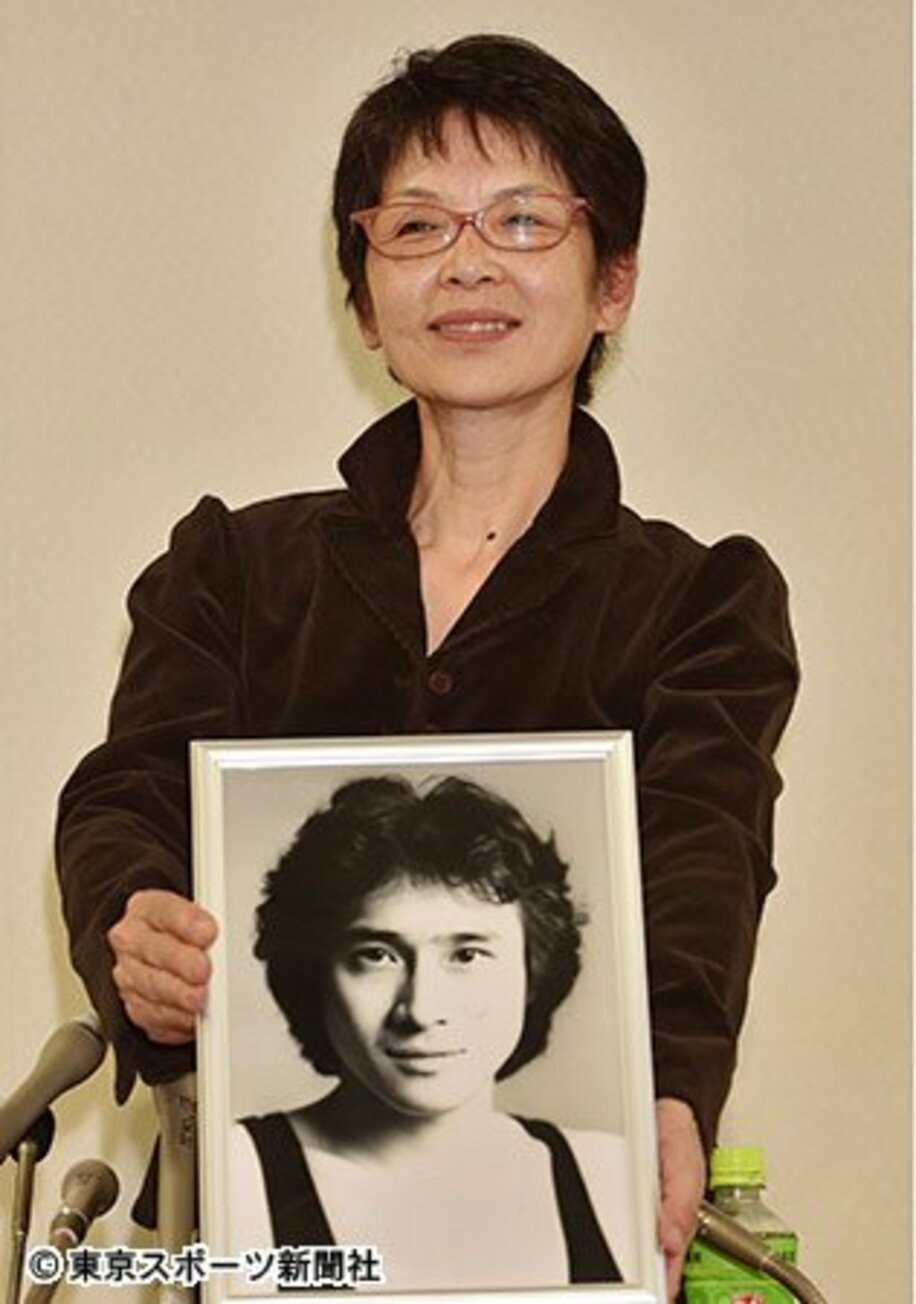 ２０歳のころの萩原さんの写真を持って会見する妻まゆ美さん