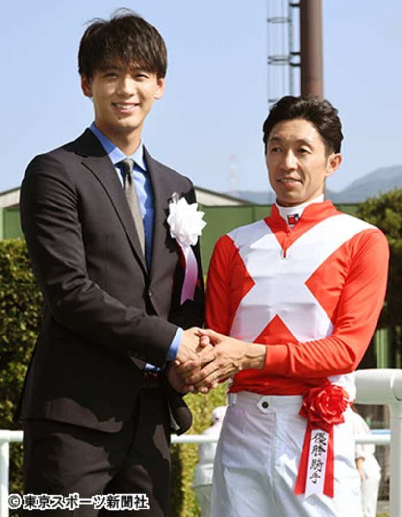  武豊（右）とがっちり握手するプレゼンターの竹内涼真