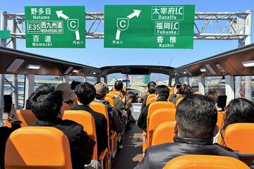 ほぼ目線の高さで道路標識の下を通過する福岡オープントップバス