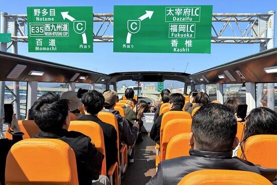 ほぼ目線の高さで道路標識の下を通過する福岡オープントップバス