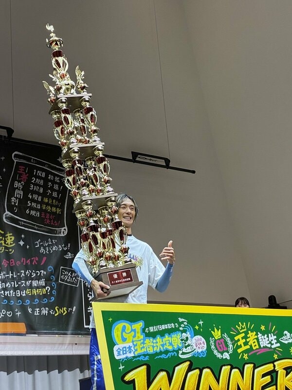 巨大すぎるトロフィーを抱え、笑顔の峰竜太