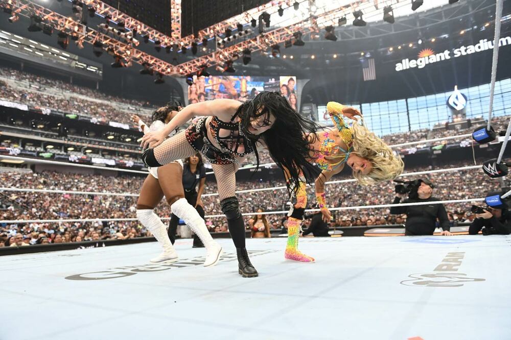 ペイジ（手前）はシャーロット・フレアー（右）とダブルのスーパーキックをラッシュ・レジェンドに叩き込む©WWE