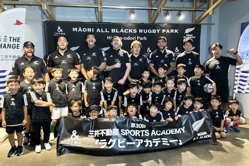 ハカの舌出しポーズで、子供たちとの記念撮影を行ったマオリ・オールブラックスの選手たち