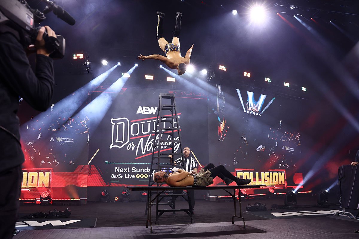 テーブル上でゲバラ(上)の超高層スワントーンボムを浴びるアリン(©All Elite Wrestling)