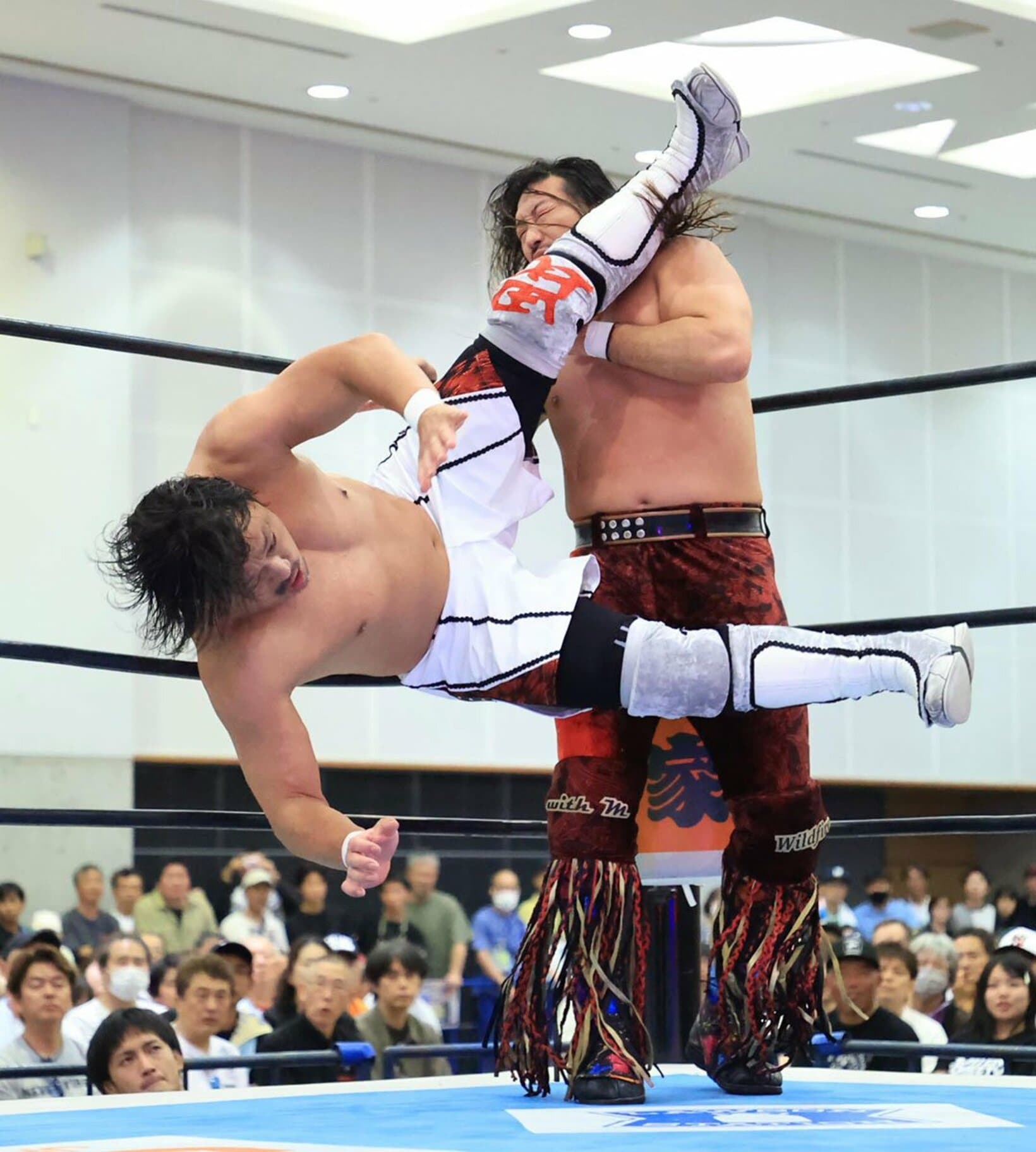 辻陽太(奥)に強烈なフライングニールキックを放つ後藤洋央紀