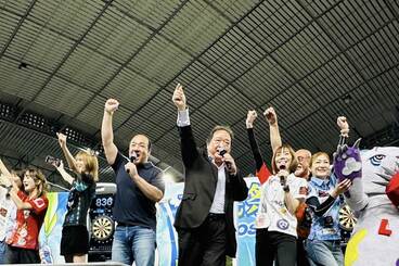 東京スポーツ新聞社・平鍋幸治社長（中央）と、にしたんクリニック・西村誠司社長（左）。周囲はダーツのプロ選手など