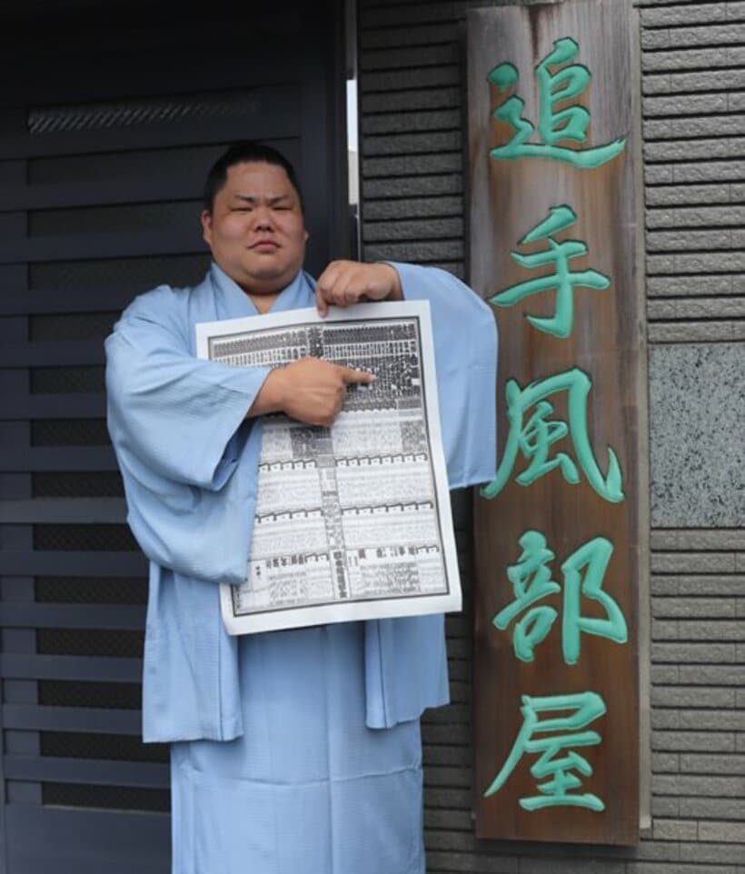  秋場所の新番付を手に部屋の前に立つ大栄翔