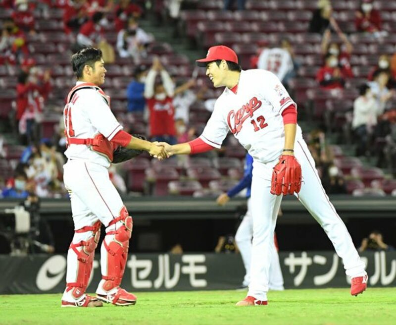  完封で５勝目をあげ、坂倉と握手する広島・九里（右）