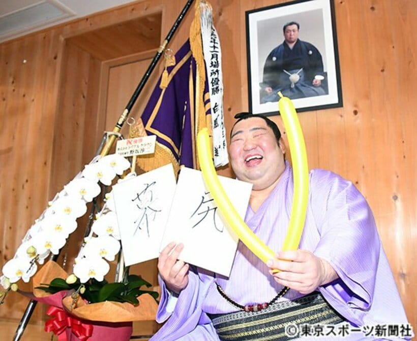  「幕尻」の色紙とＶをかたどった風船を持った徳勝龍は満面の笑み