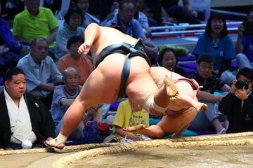 錦木に押し倒しで敗れた炎鵬（右）