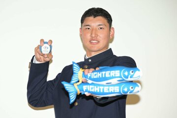 日本ハムグッズを手に記念撮影する山梨学院・菰田