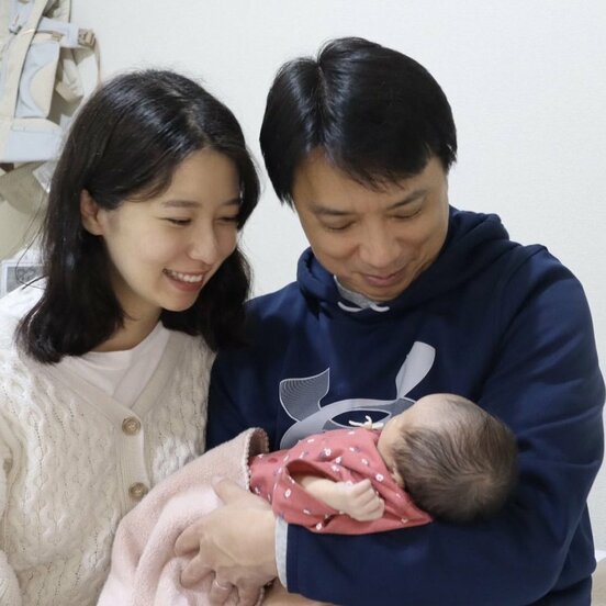  誕生した第一子女児を抱き、笑顔を見せる西岡氏と友寄夫婦