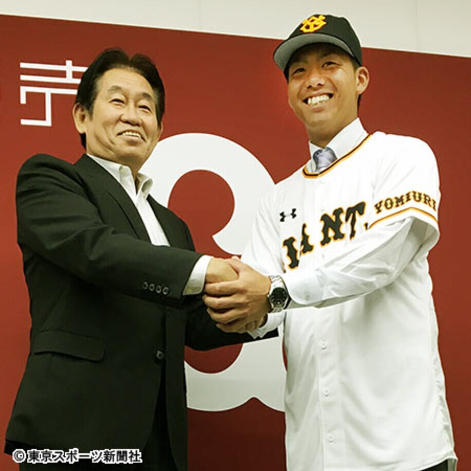  鹿取GM（左）と笑顔で握手する田中貴也