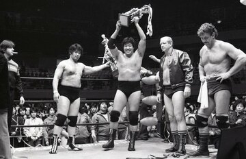  試合後のセレモニーで笑顔でトロフィーを掲げる鶴田。左隣の天龍はぶぜんとした表情（東スポWeb）