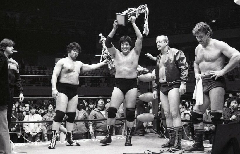  試合後のセレモニーで笑顔でトロフィーを掲げる鶴田。左隣の天龍はぶぜんとした表情（東スポWeb）