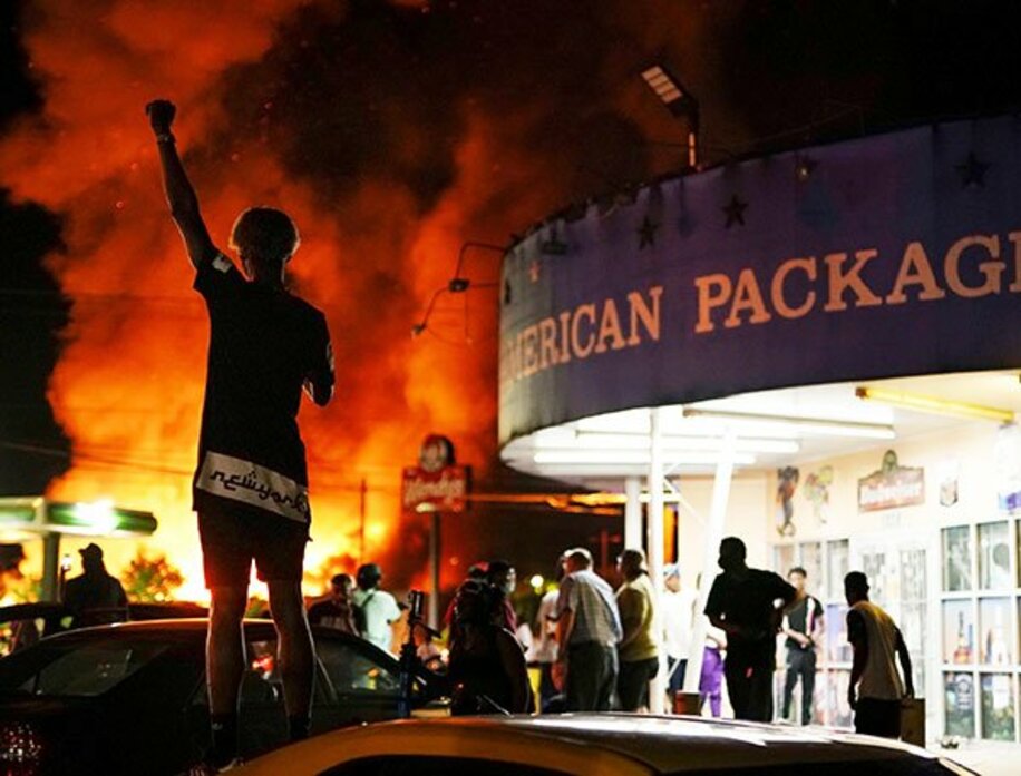  炎上した現場のハンバーガー店を眺めるデモ参加者（ロイター）