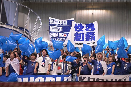 青い袋を手に応援する日本サポーター
