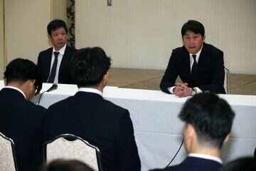 全体ミーティングで話す新井貴浩監督（右）