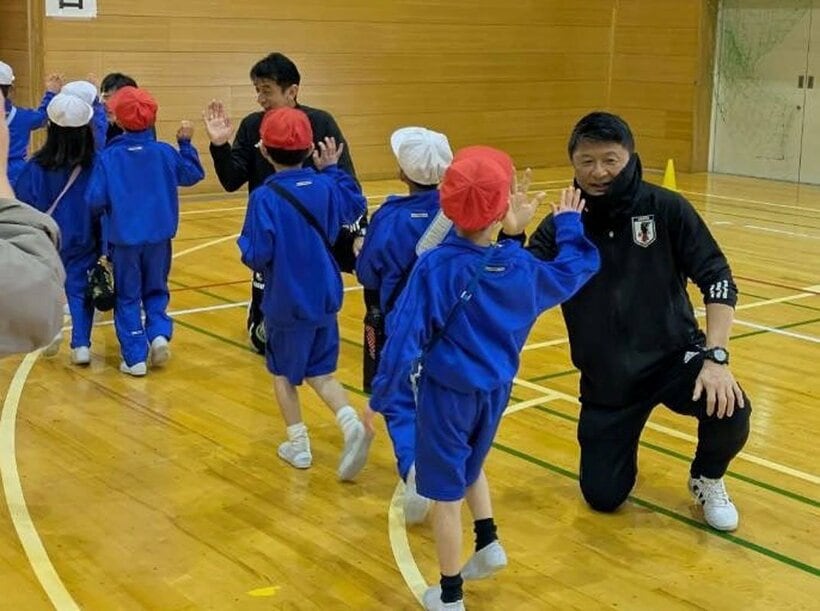 小学生とハイタッチを交わす武田修宏氏（手前）。左奥は井原正巳氏