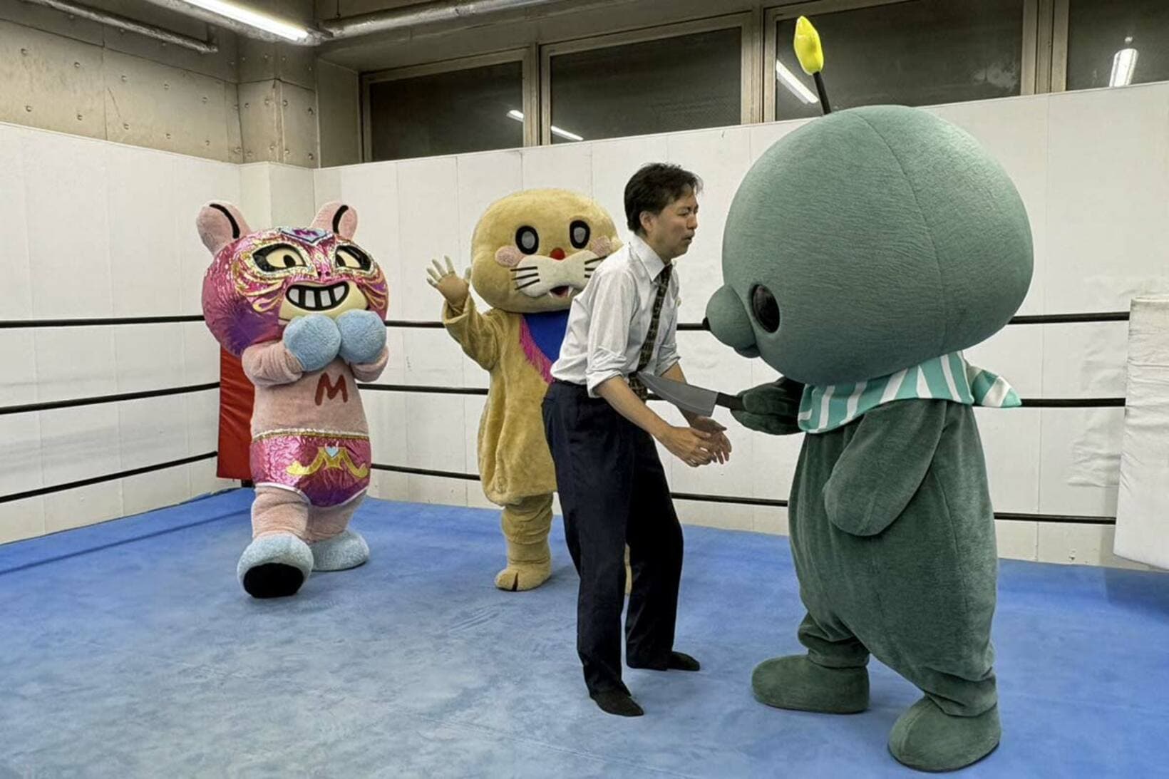 甲田哲也代表（右から二番目）を刃物で襲うタマ（右）、驚く魅仁夢（左）とポコたん