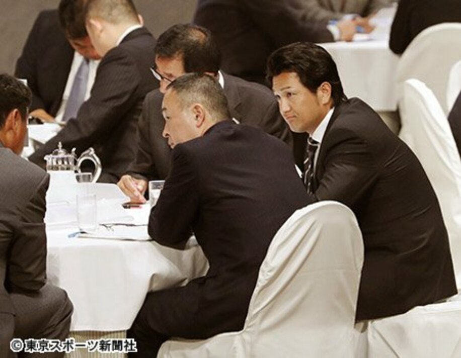 ドラフト会議のテーブルで険しい表情を見せる由伸監督（右）