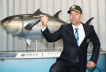  近大マグロの模型の前でポーズをとる近大・佐藤