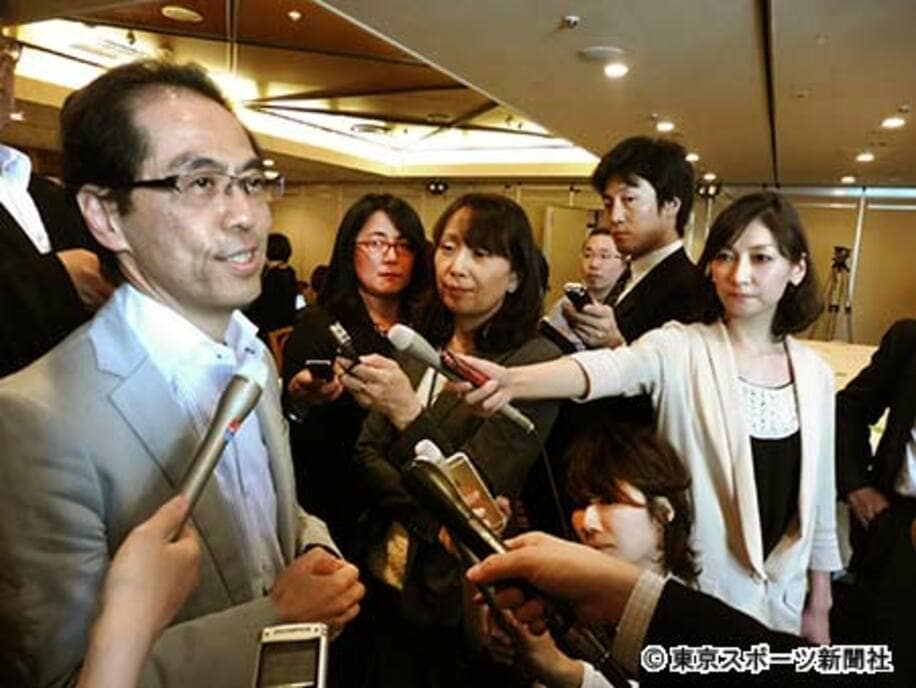 日本の報道陣に囲まれ、バトルを展開した古賀氏（左）