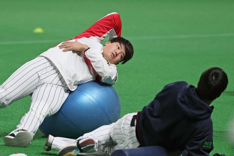 バランスボールを使ってストレッチするヤクルト・村上(左)