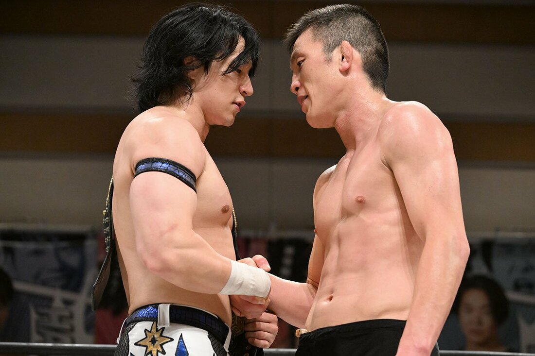上野勇希(左)と握手しながらにらみ合う青木真也