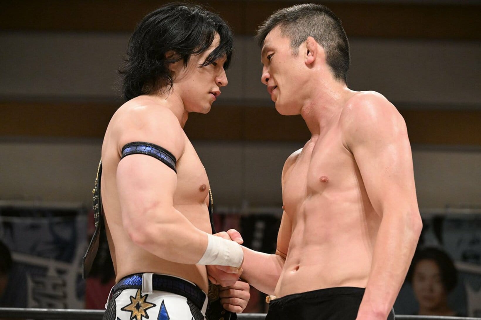 上野勇希(左)と握手しながらにらみ合う青木真也