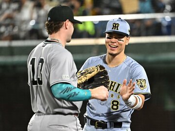 守備から戻るキャベッジ（左）を迎える佐藤輝明