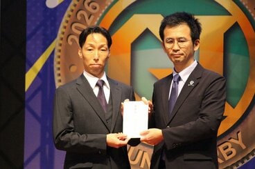 北九州市・館圭輔副市長（右）に目録を渡す川上剛支部長