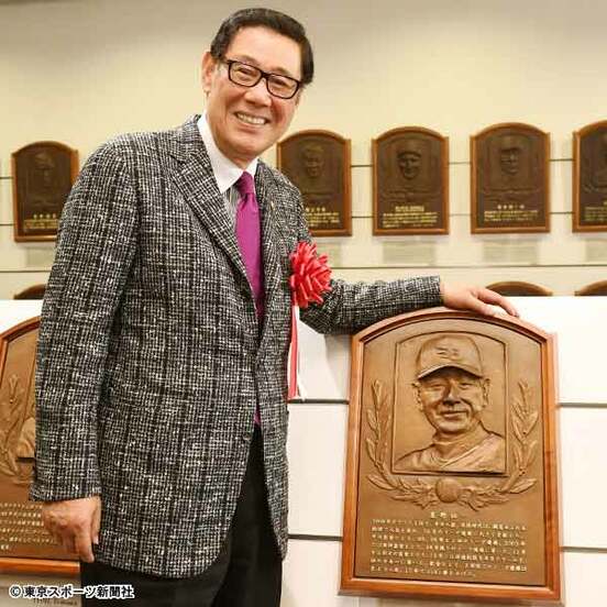 星野氏のレリーフの前で笑顔を見せる田淵氏