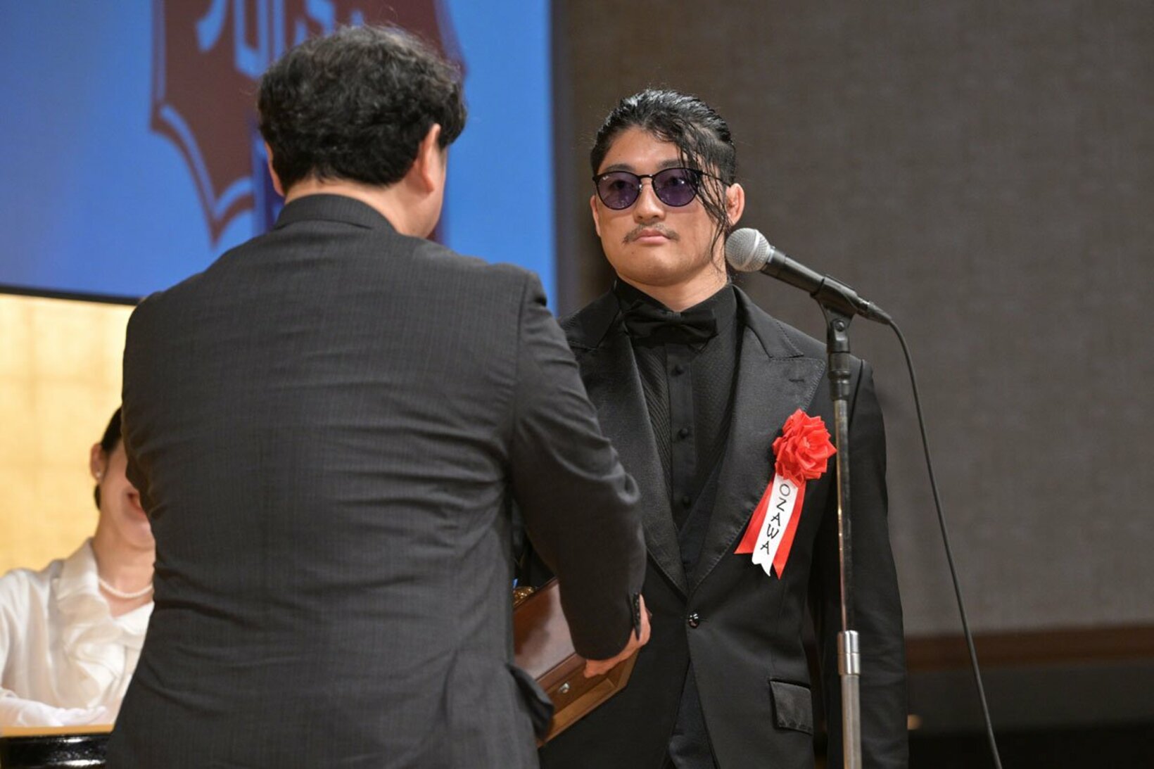 賞状とトロフィーを片手で受け取るOZAWA（右）