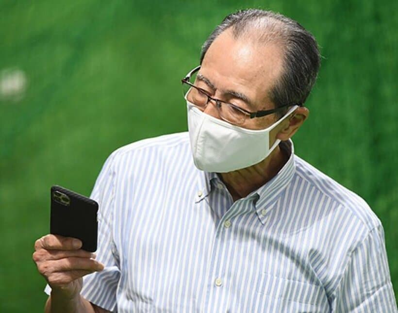 スマホを持つ王会長。タブレットなども使いこなすという