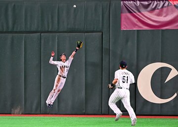 ９回、この大飛球をジャンピングキャッチした侍ジャパン・周東佑京(左)