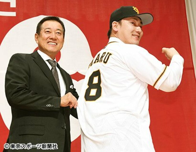  入団会見で背番号８を披露する丸。左は原監督