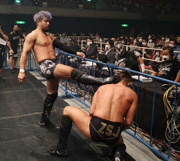  解説席のデスペラードの前で、ザック(右)を「子ども扱い」するKENTA