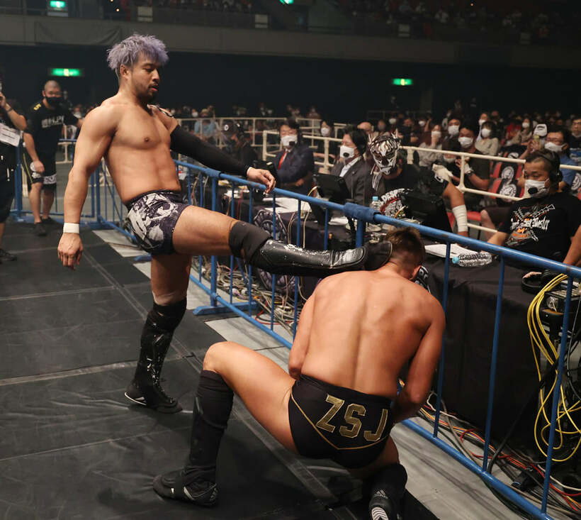  解説席のデスペラードの前で、ザック(右)を「子ども扱い」するKENTA