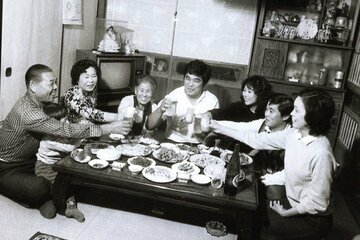 大学時代に実家で食事をする谷津嘉章（左から４人目・本人提供）