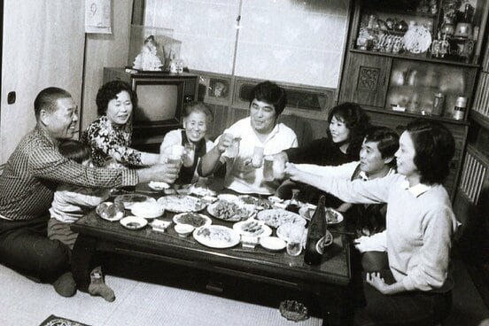 大学時代に実家で食事をする谷津嘉章（左から４人目・本人提供）