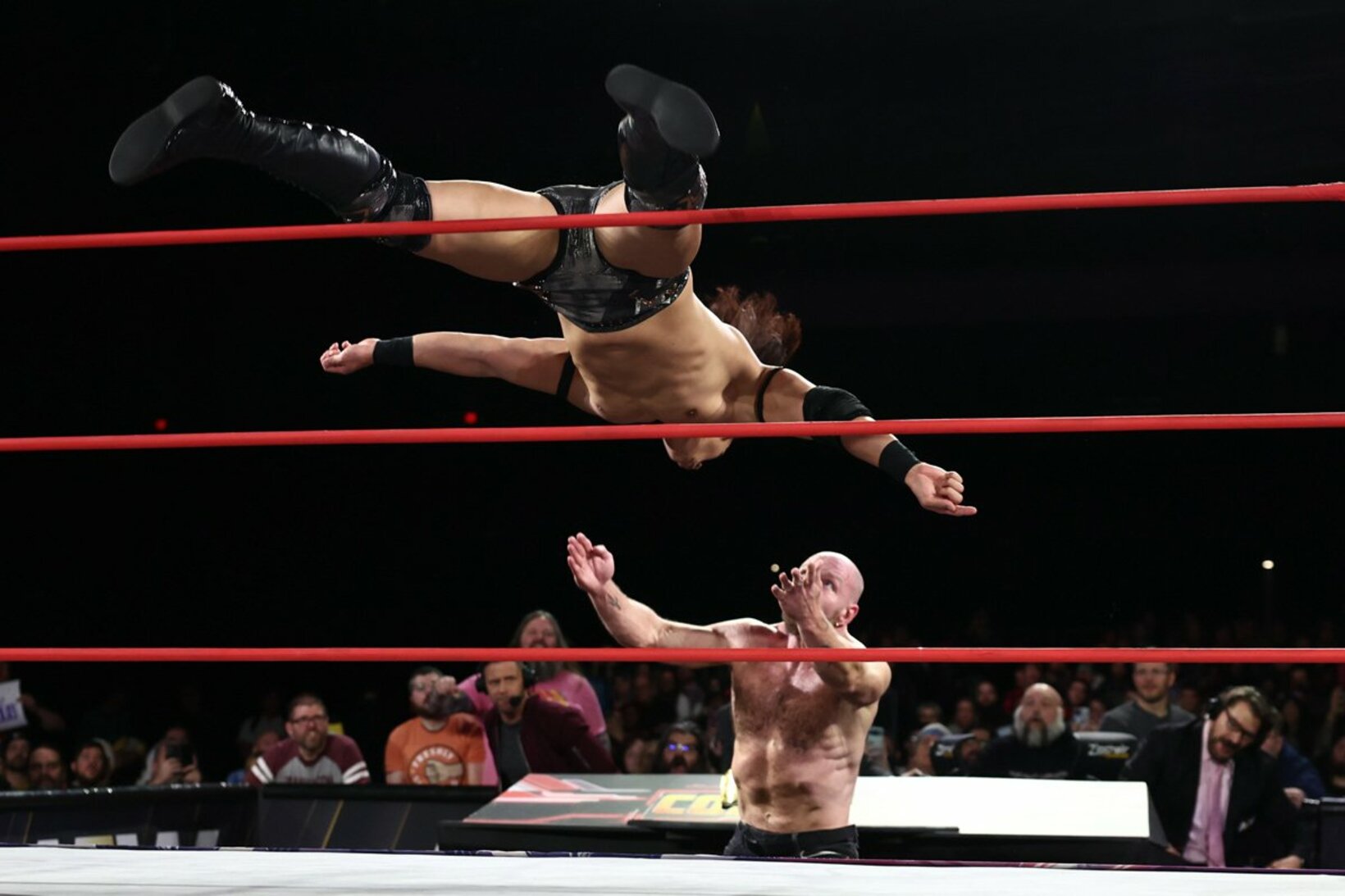ジョン・モクスリー（下）にノータッチ式トペ・コンヒーロを発射する竹下幸之介©All　Elite　Wrestling