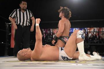  遠藤（後方）に辛勝した秋山はリングに横たわったまま拳を突き上げた