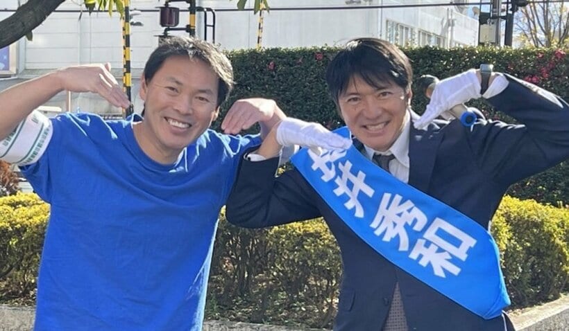 応援に駆け付けたスマイル党の込山洋氏（左）とスマイルポーズを決めた長井秀和