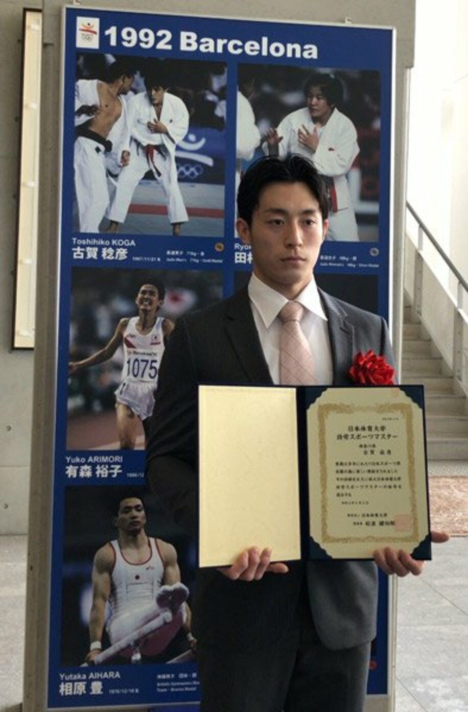  古賀稔彦さんに授与された功労スポーツマスターの証書を掲げる長男の颯人氏
