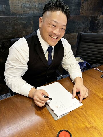 笑顔で契約書に捺印する河上隆一