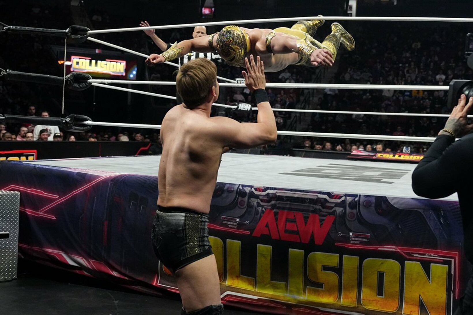 オカダ・カズチカ（手前）にトペ・スイシーダを浴びせるマスカラ・ドラダ　©All Elite Wrestling